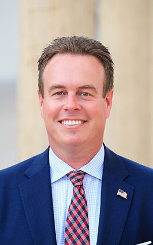 A man in a suit and tie is smiling for the camera. Casey McKeon