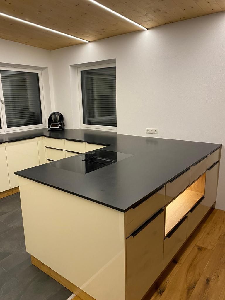 Eine moderne Küche mit cremefarbenen Schränken, schwarzen Arbeitsplatten