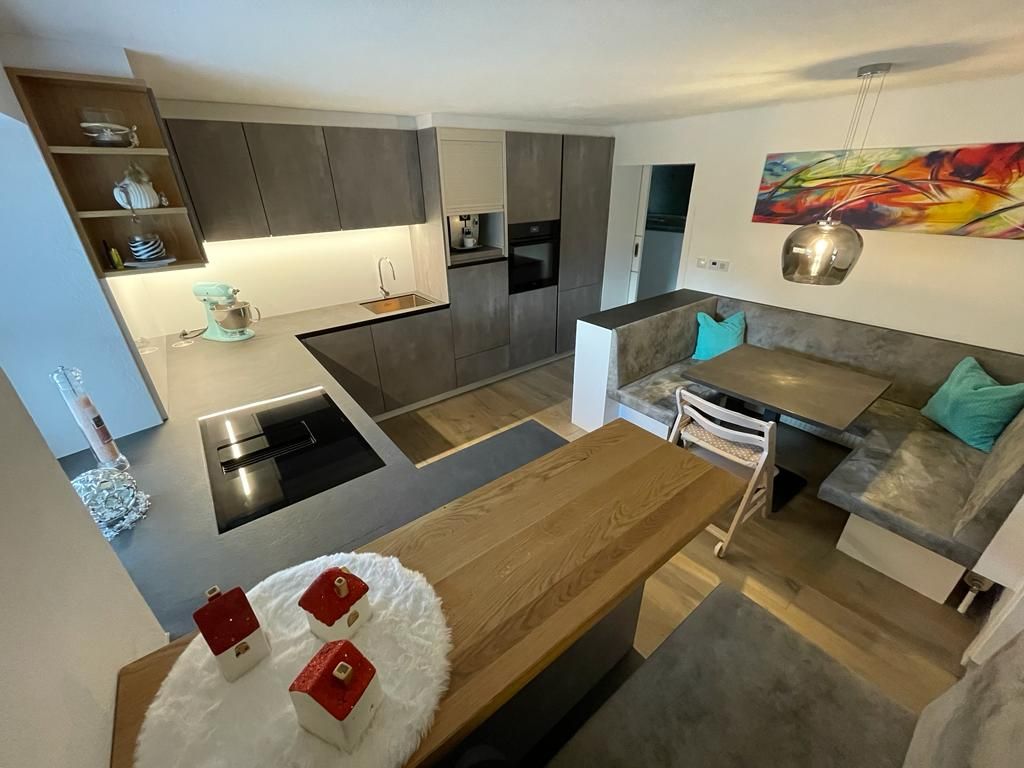 Moderne Küche mit grauen Schränken, integrierten Geräten, einer Kochinsel aus Holz