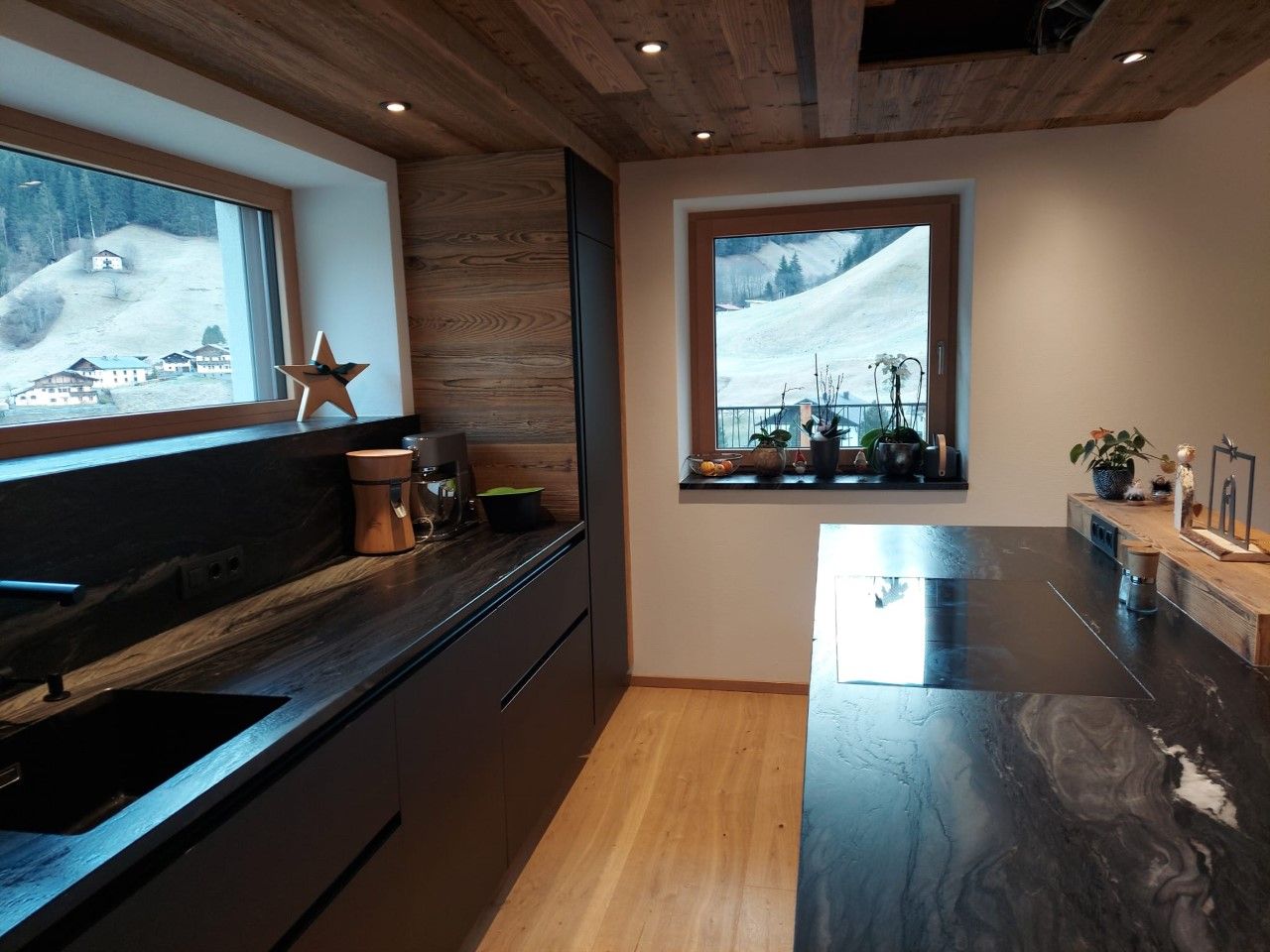 Eine moderne Küche mit dunklen Steinarbeitsplatten, holzgetäfelten Wänden und Decke