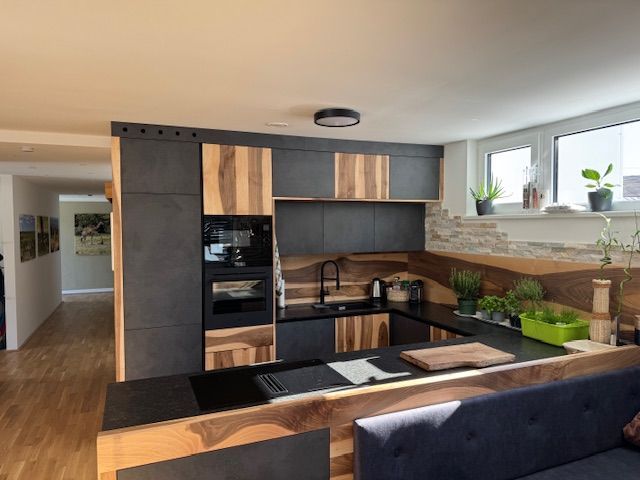Eine moderne Küche mit dunkelgrauen Schränken und Akzenten aus Naturholz