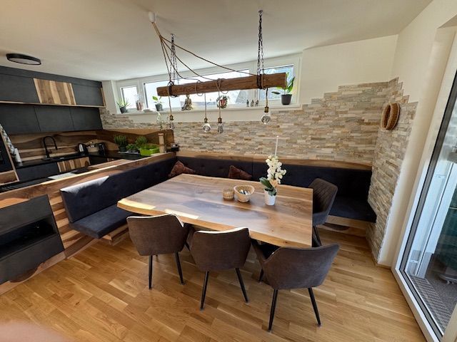 Ein moderner Essbereich mit Holztisch, dunklen Stühlen, einer eingebauten Eckbank und einer einzigartigen Hängeleuchte.