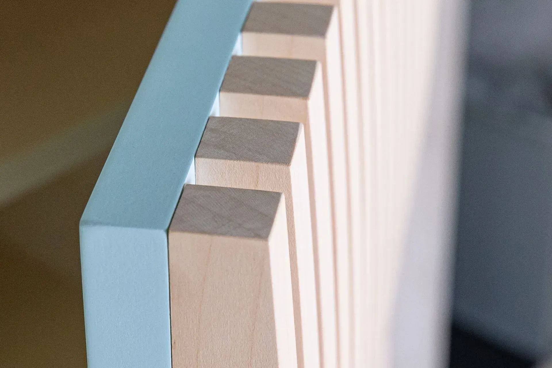 Nahaufnahme einer hellblauen Zierleiste neben einer Reihe vertikaler, hellfarbiger Holzlatten.