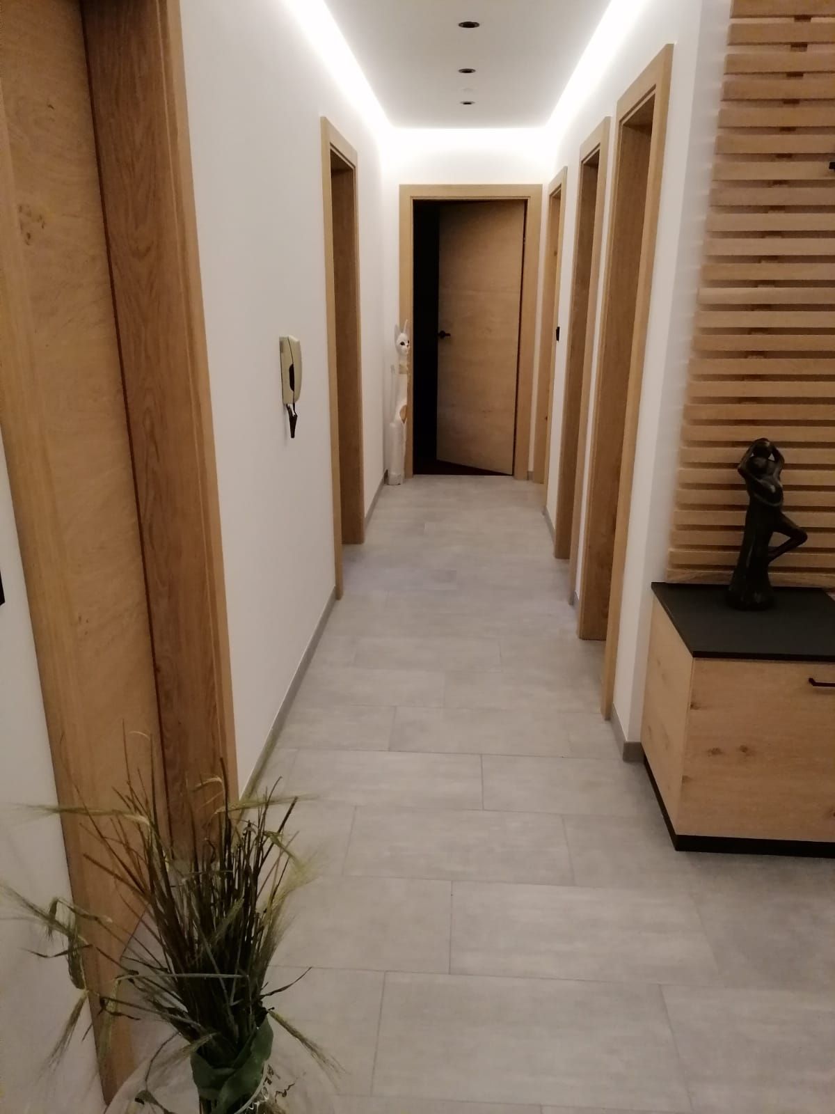 Ein moderner Flur mit hellen Fliesenböden, Türrahmen aus Holz