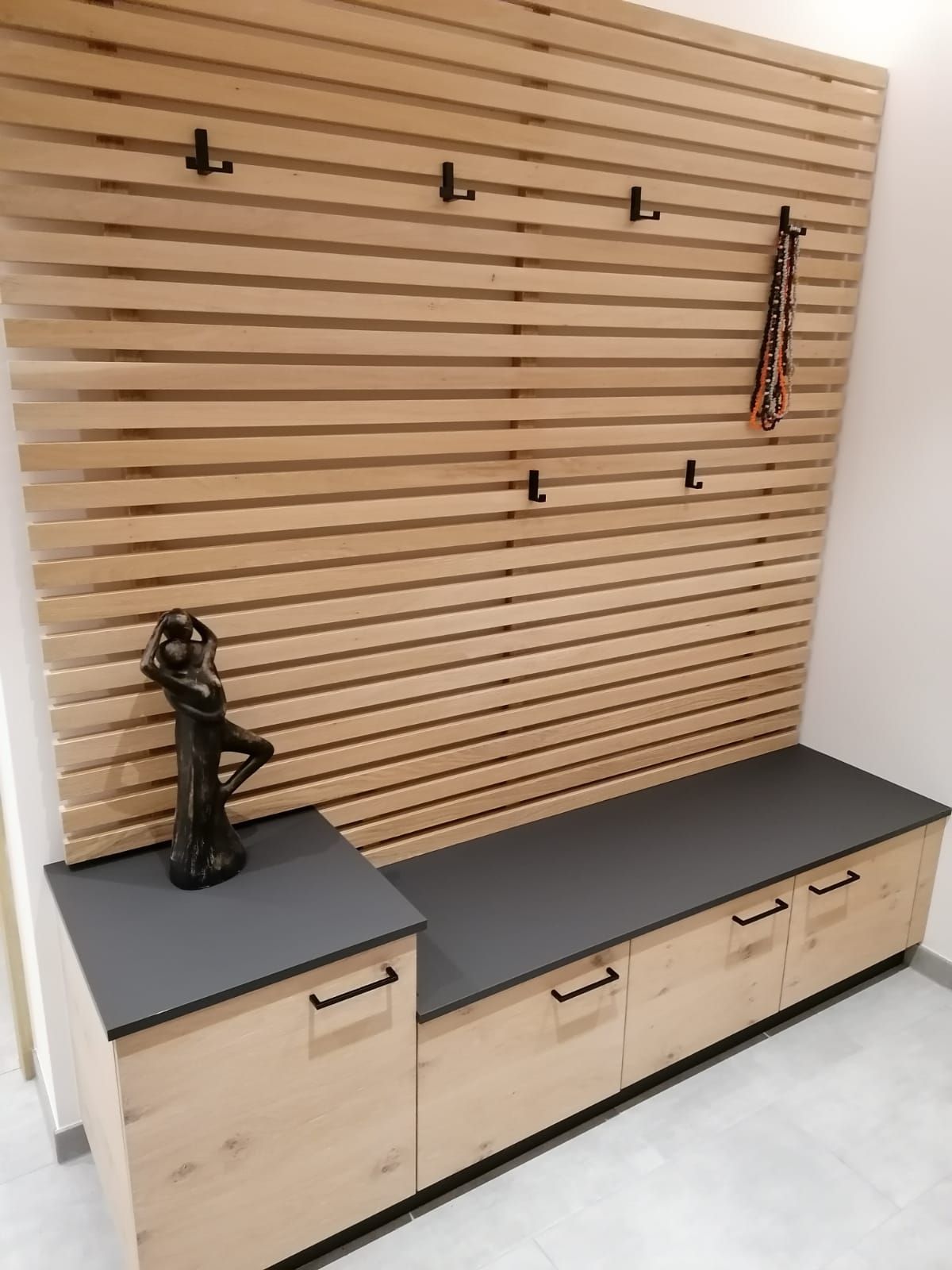 Eine helle Holzbank im Eingangsbereich mit grauer Sitzfläche