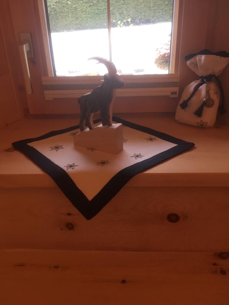 Eine hölzerne Steinbockfigur steht auf einem weißen, quadratischen Tuch