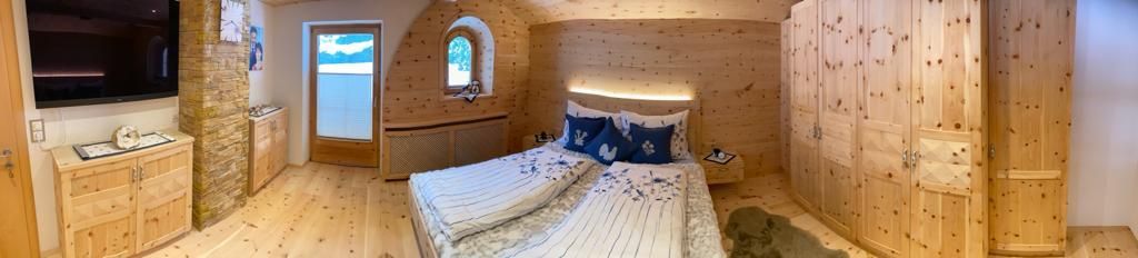 Panoramablick auf ein gemütliches Schlafzimmer mit hellen Kiefernholzwänden