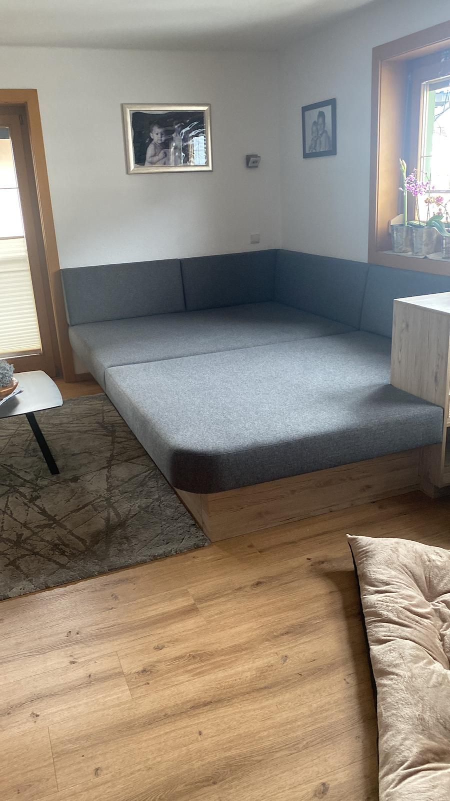 Eine grau gepolsterte Ecksitzgruppe in einem Wohnzimmer mit Holzboden