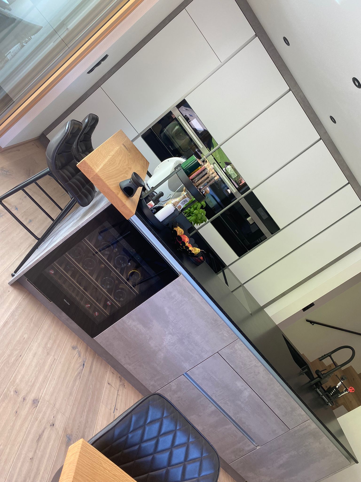 Eine moderne Kücheninsel mit Weinkühlschrank und strukturierten grauen Schränken