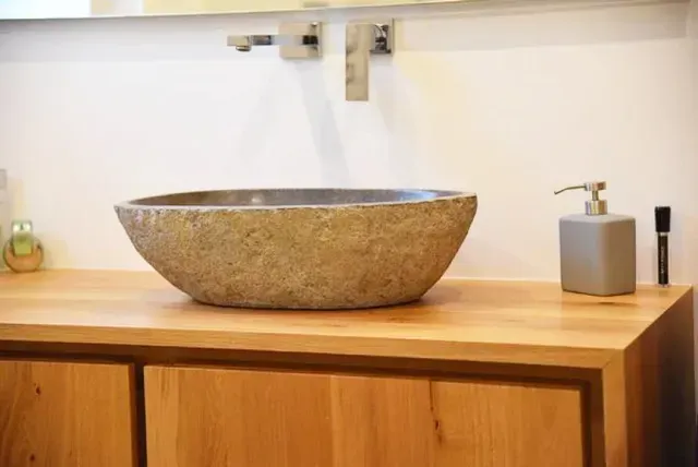 In einem Badezimmer steht ein Aufsatzwaschbecken aus Stein