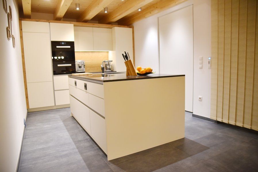 Eine moderne Küche mit cremefarbener Kochinsel, eleganten Schränken, einem eingebauten Backofen