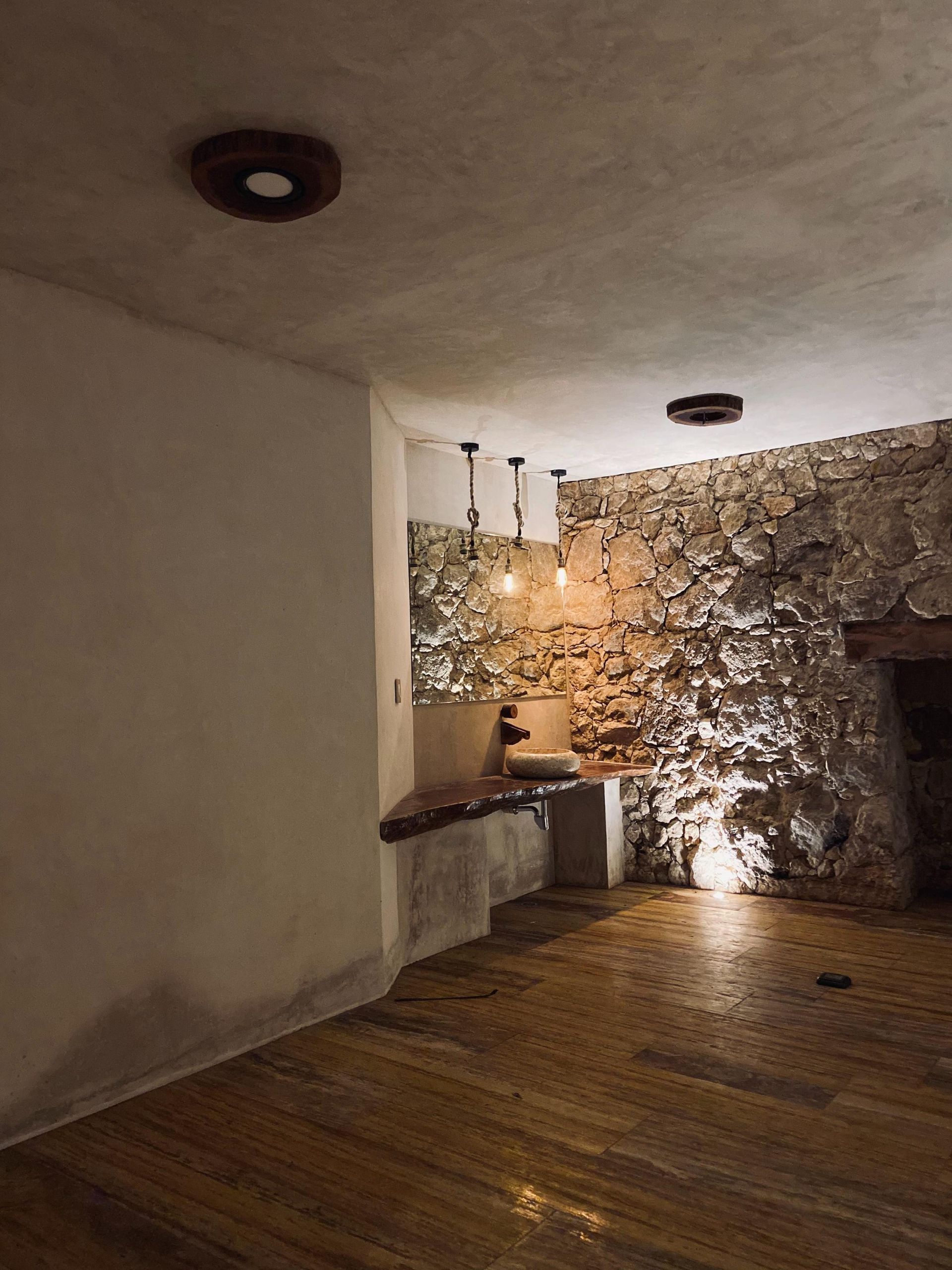 A room with a stone wall and a sink in it.
