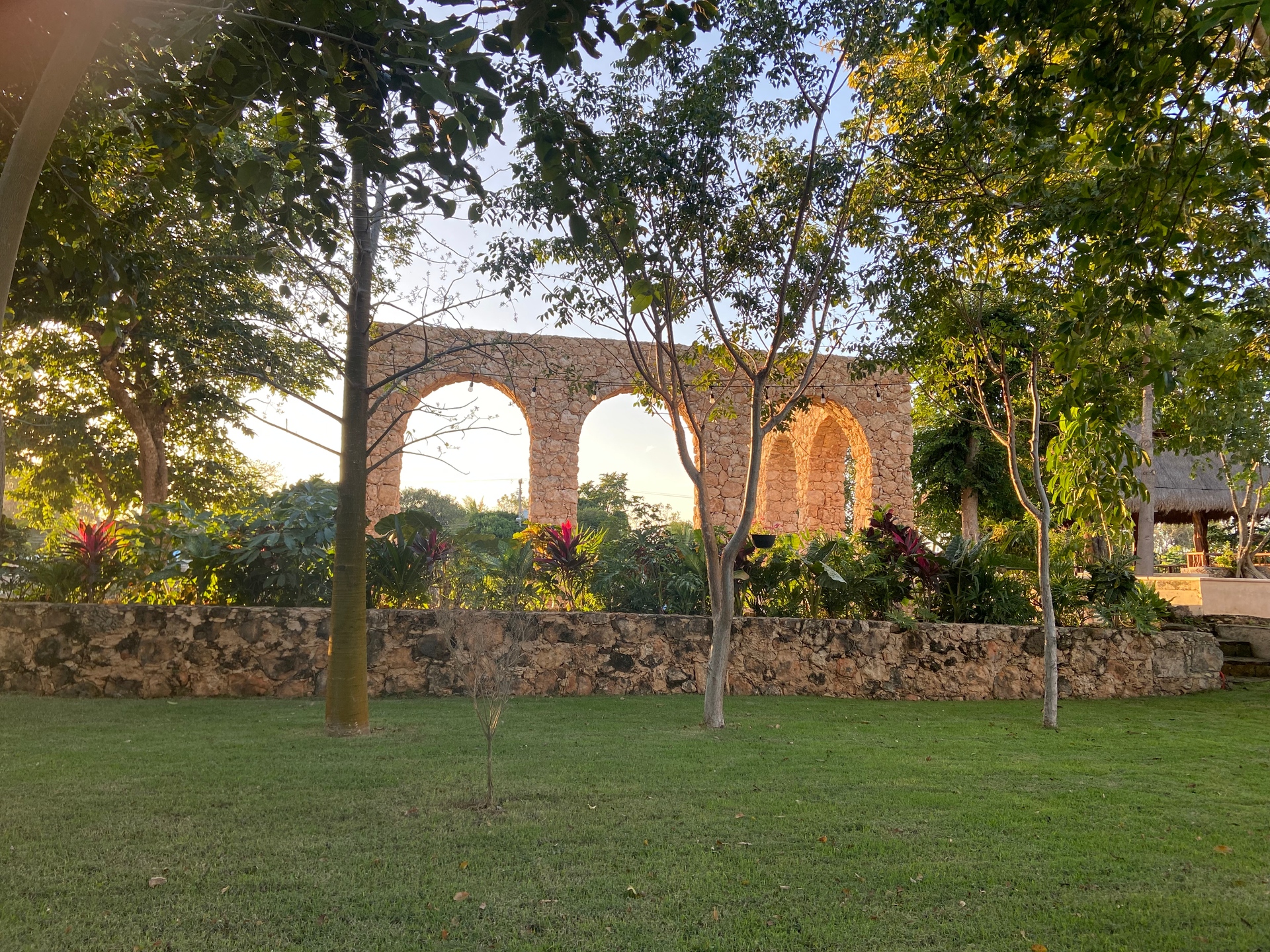 A stone bridge is surrounded by trees and grass in a park.