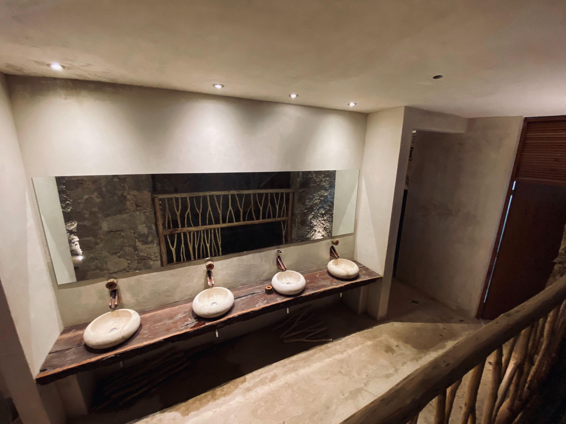 A bathroom with three sinks and a large mirror.