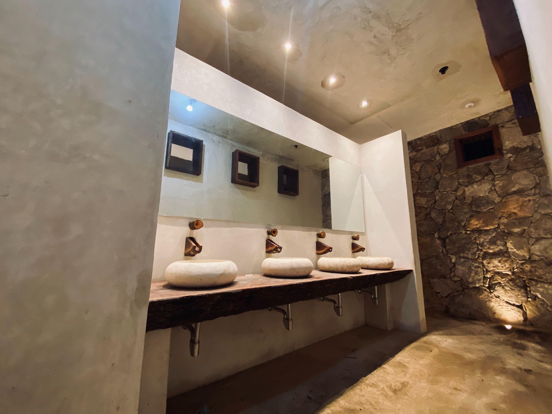 A bathroom with three sinks and a large mirror.