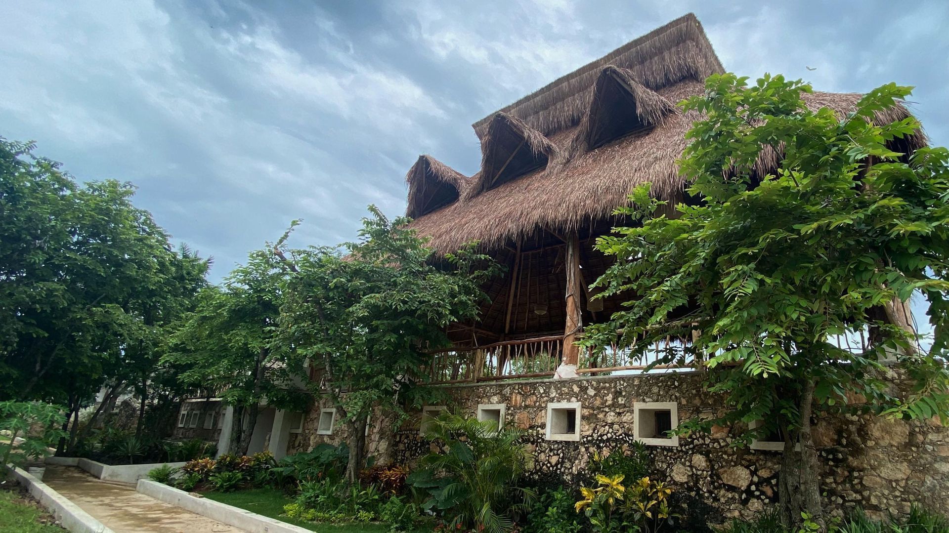 A large house with a thatched roof is surrounded by trees.