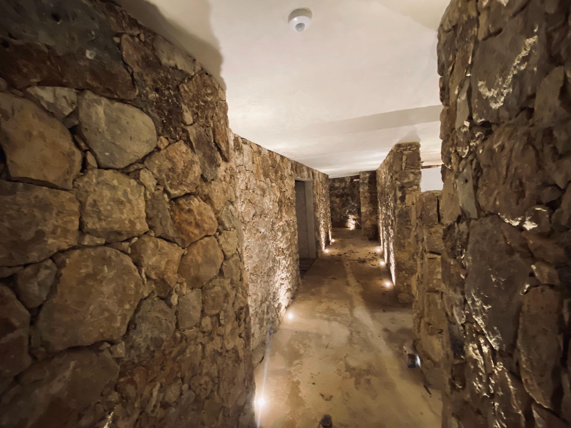 A long stone hallway with lights on the walls