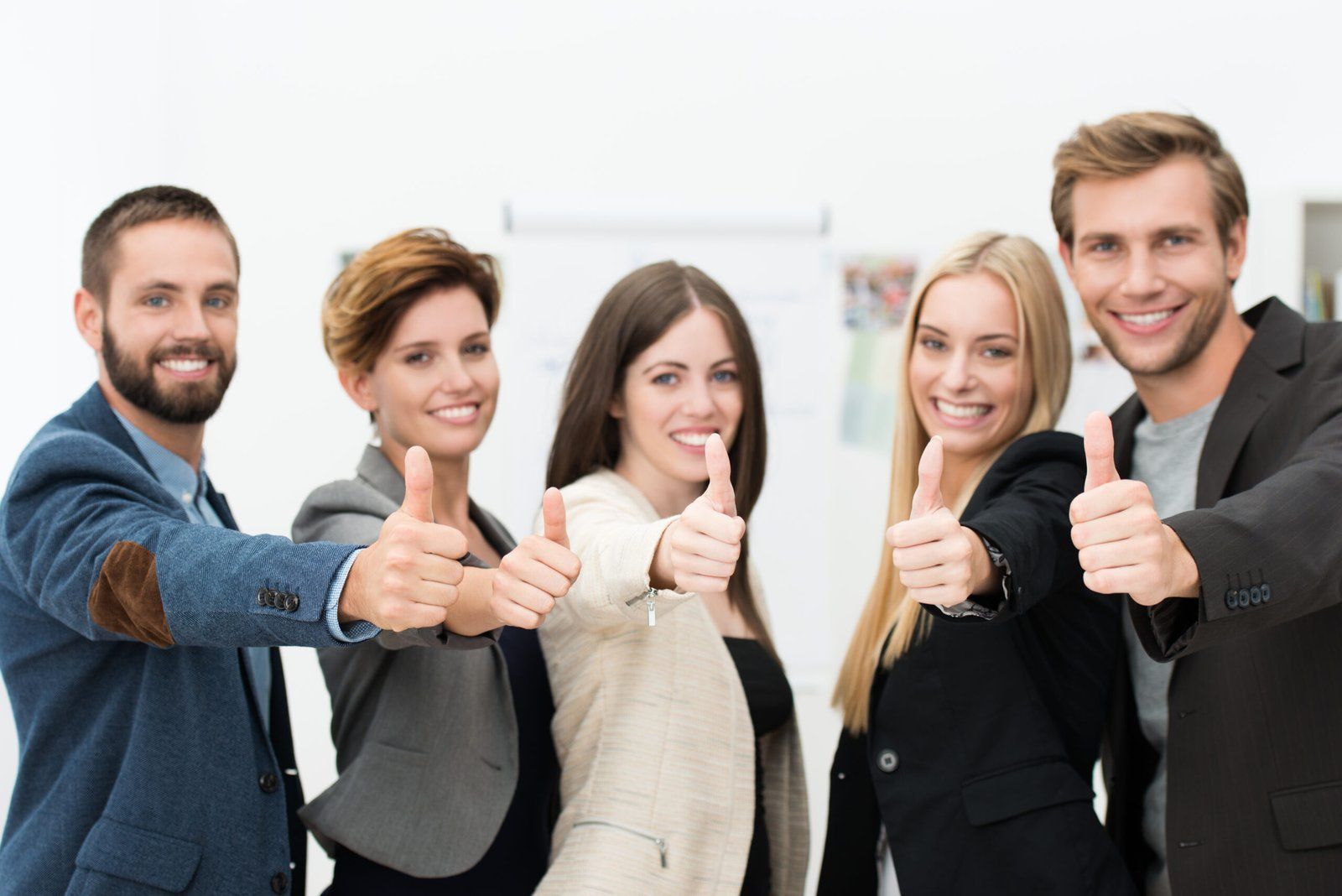 Five smiling people in business attire give thumbs up.