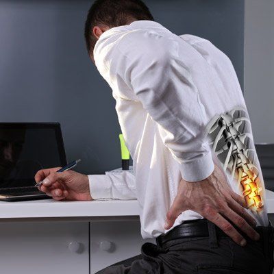 Man at desk, back pain. Skeleton view highlights spine with yellow glow.
