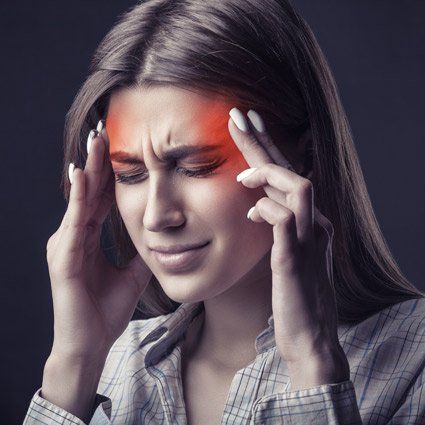 Woman holding head, with red highlight indicating pain; grimacing, eyes closed.