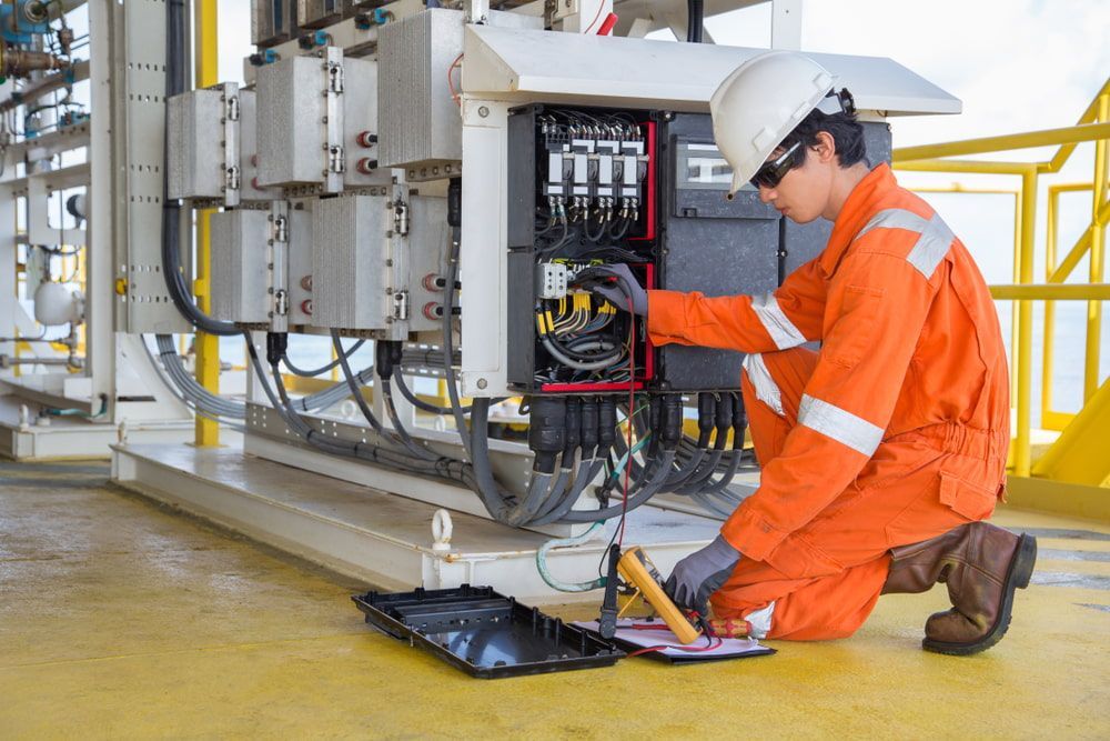 A Man In An Orange Jumpsuit Is Working On An Electrical Box —— In Electrics In Mission Beach, QLD
