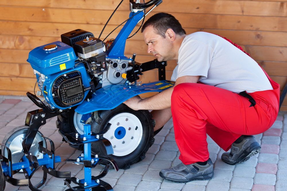 A Man In Red Pants Is Working On A Small Tractor — In Electrics In Mission Beach, QLD