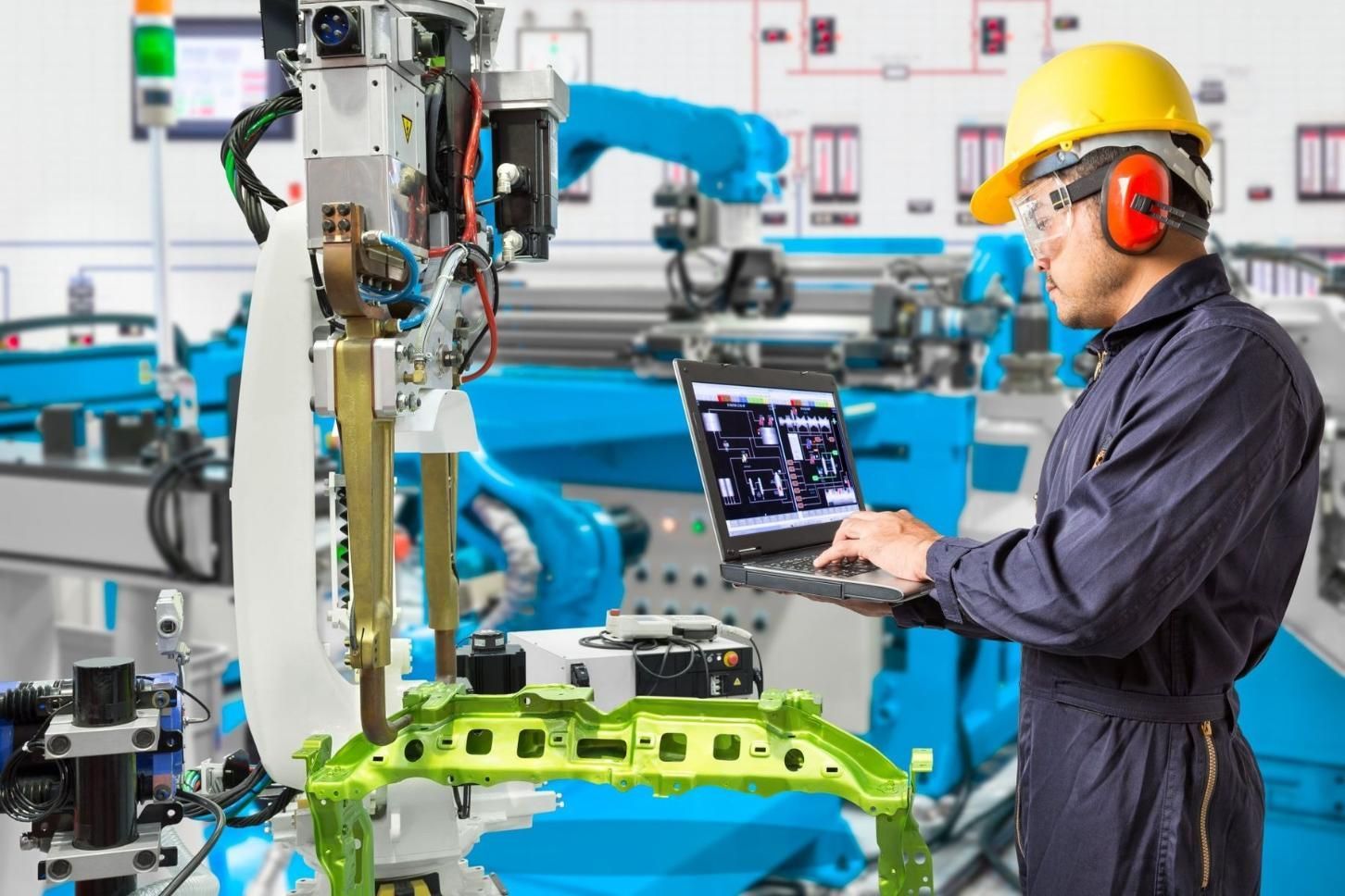 A Man Is Using A Laptop Computer In A Factory — In Electrics In Mission Beach, QLD