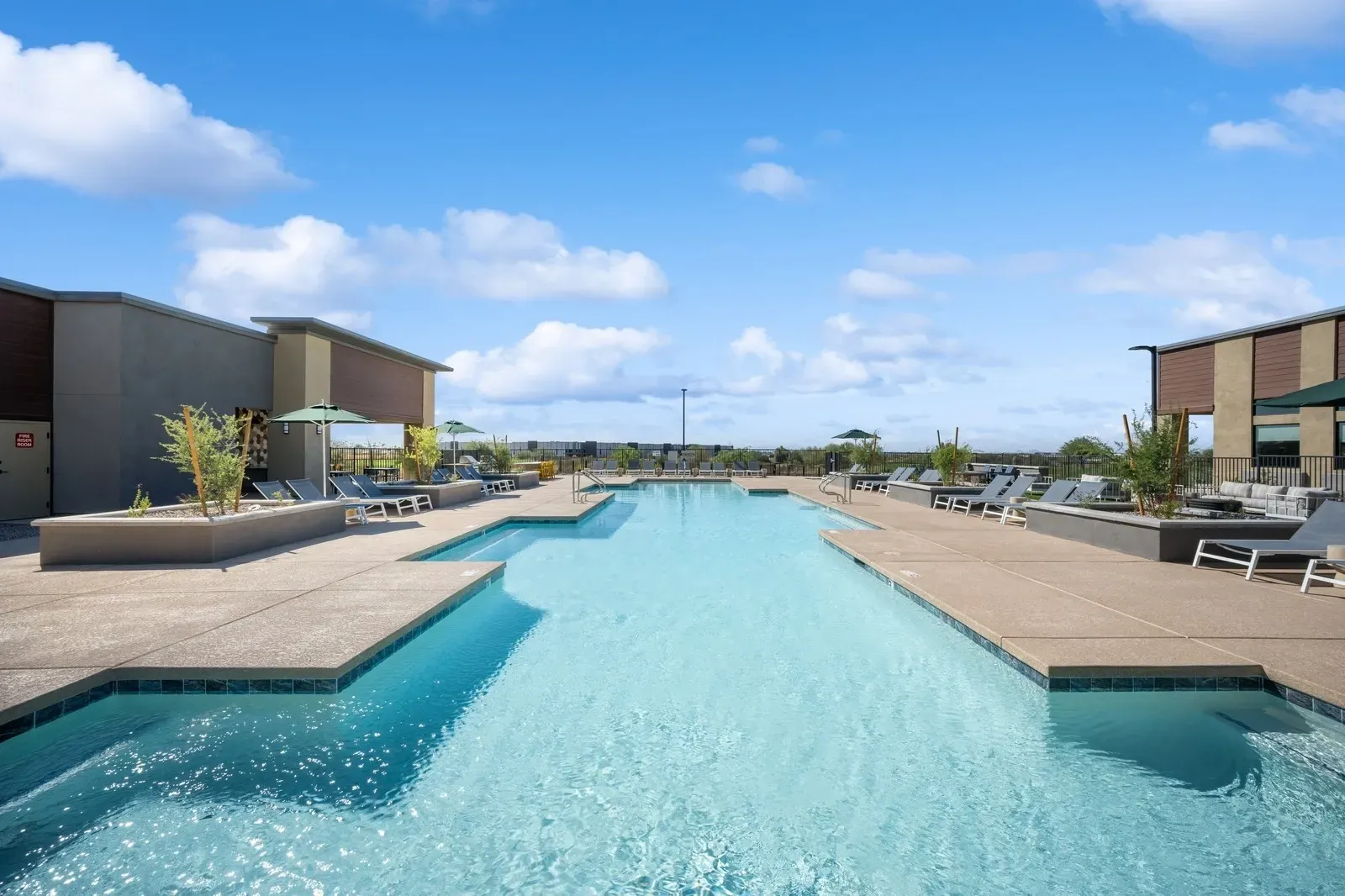 Outdoor swimming pool with lounge chairs and umbrellas at Longbow Luxury Apartments Mesa, AZ.