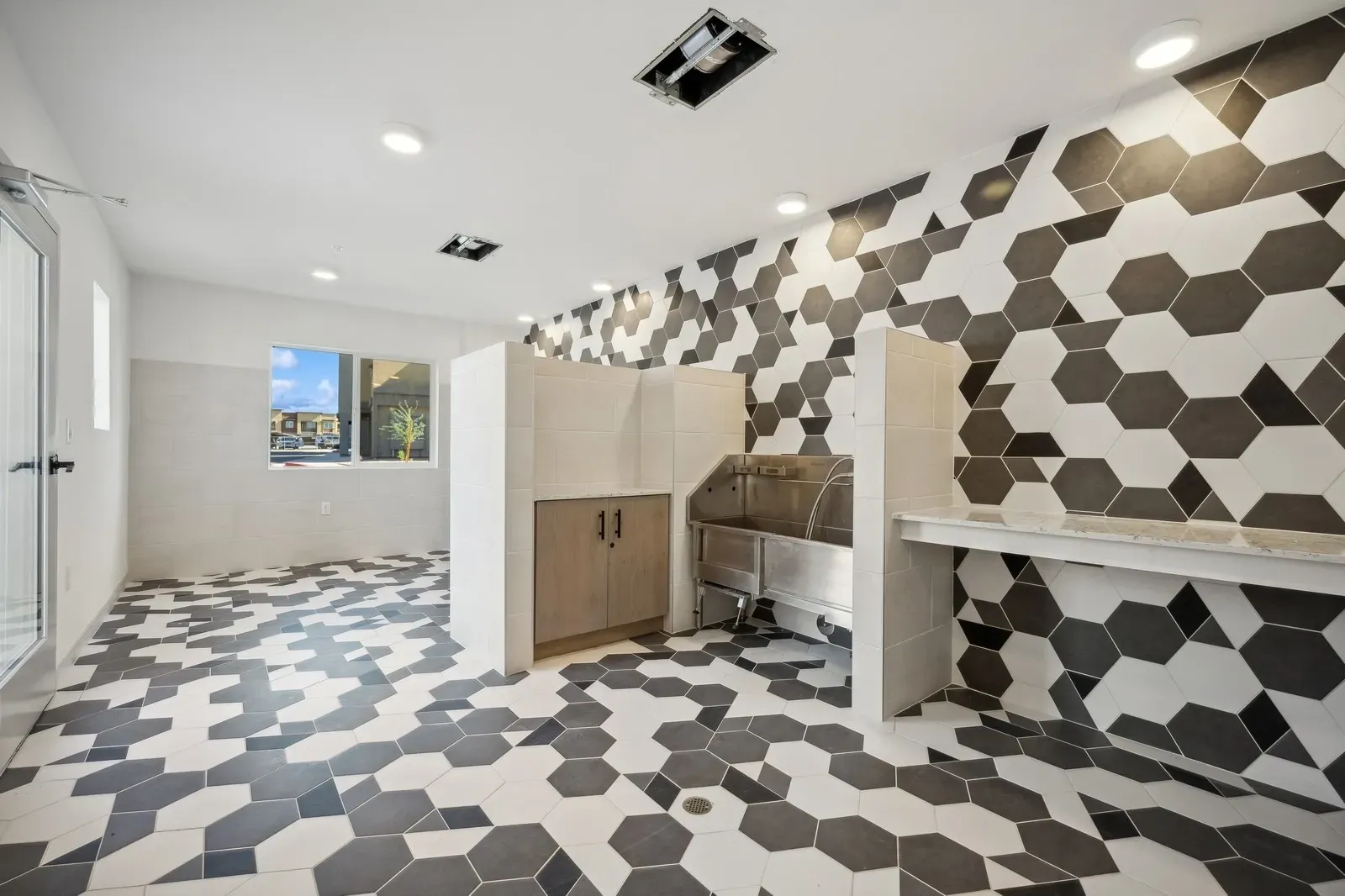 Modern pet grooming station with stainless steel tub and stylish hexagonal tile at Longbow Luxury Apartments Mesa, AZ.