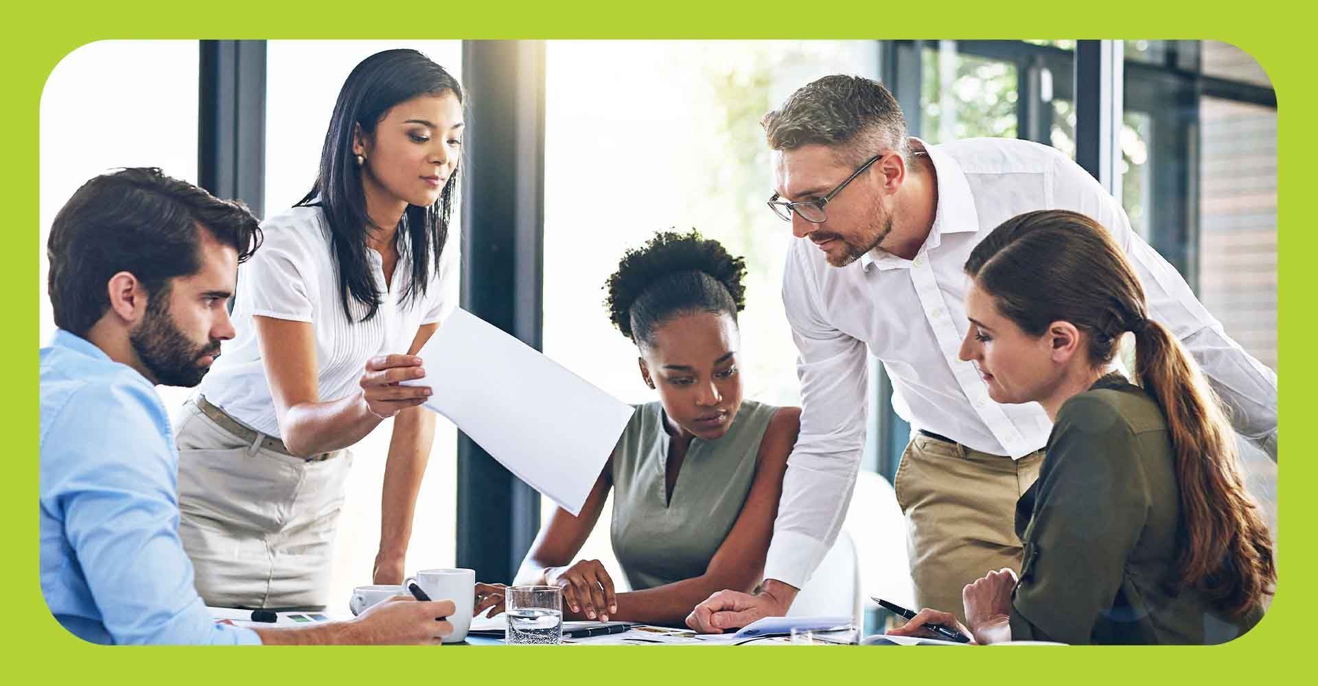 A group of business professionals reviewing paperwork at a conference table.