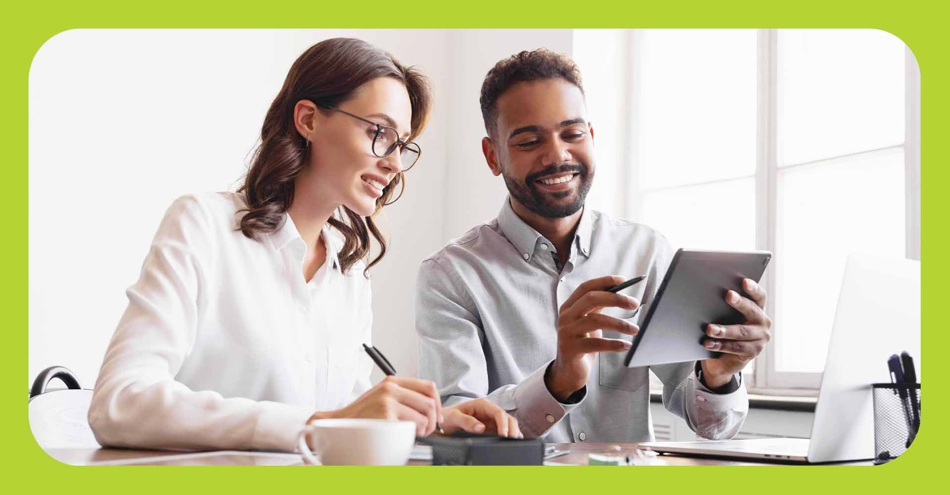 A man and a woman looking at a tablet in a business setting.