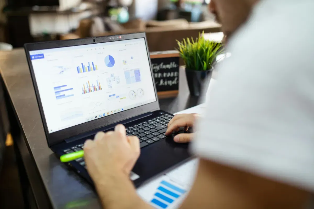 A person is using a laptop computer with a graph on the screen.