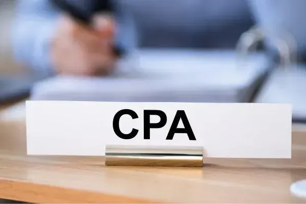 A sign that says cpa is on a wooden table.