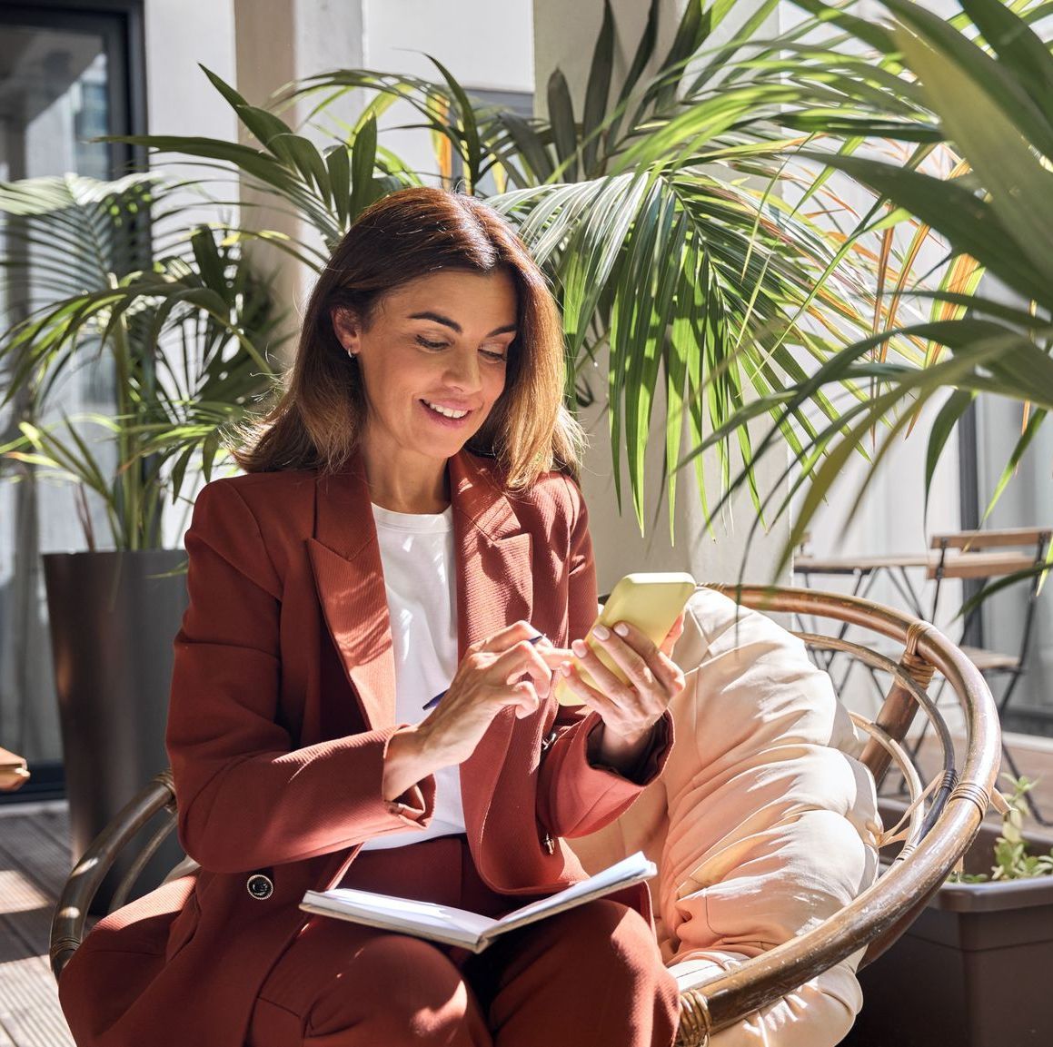 A woman in a suit is sitting in a chair looking at her phone getting ready to call nth degree cpas to discuss a new tax strategy