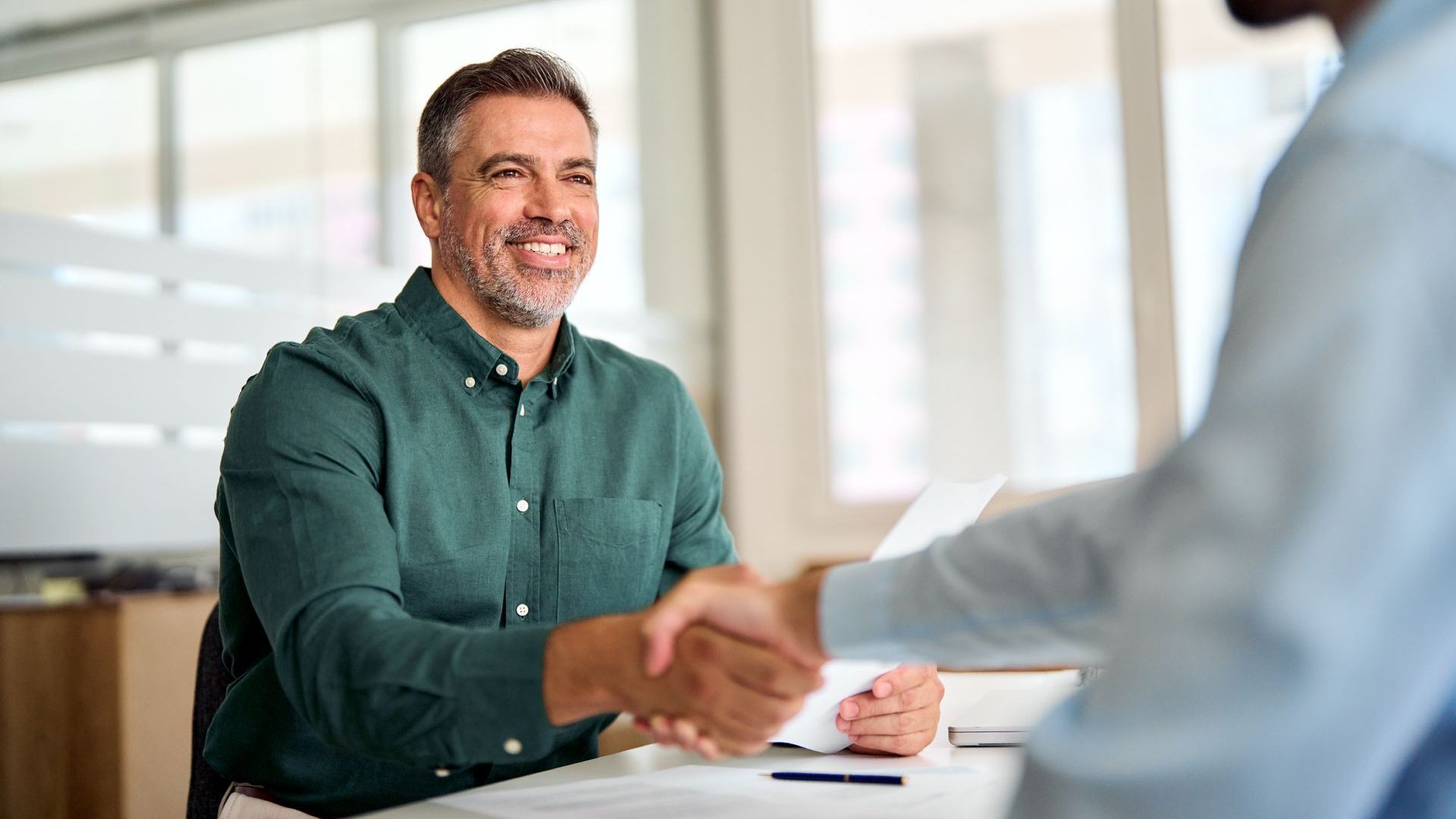 A man is shaking hands with another man during a job interview.