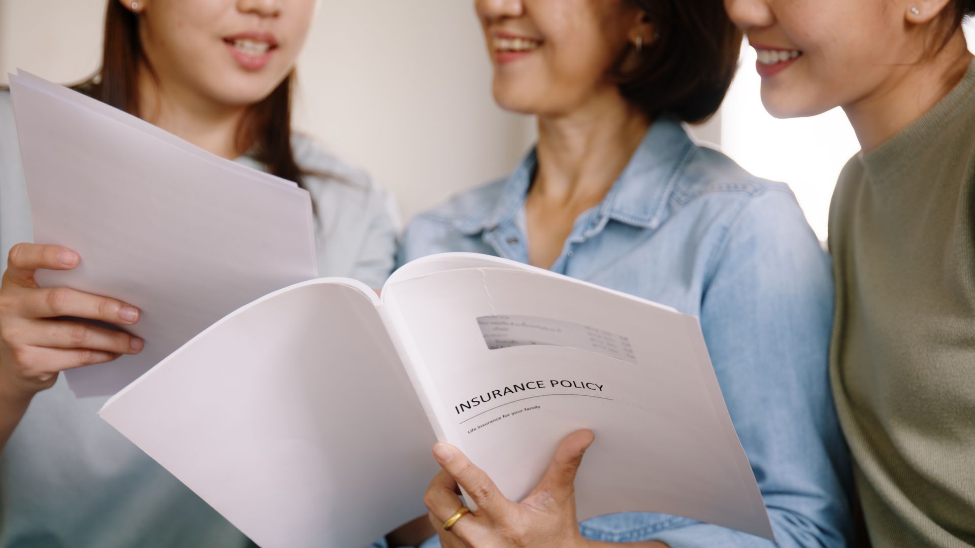 Three women are sitting next to each other looking at a book.