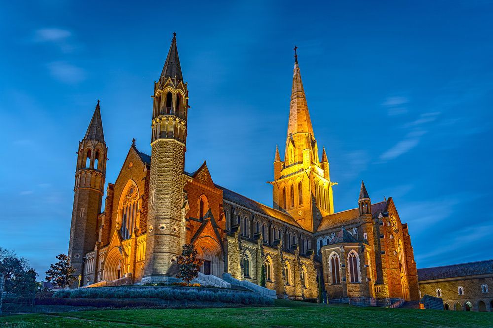Gothic-style cathedral with illuminated spires against a twilight blue sky.
