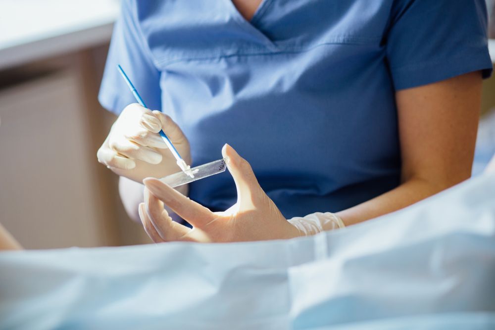 a Medical Professional in Blue Scrubs and Gloves Performs a Pap Smear — DAB Services in Moranbah, QLD