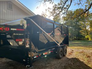 A dump trailer is parked in front of a house.