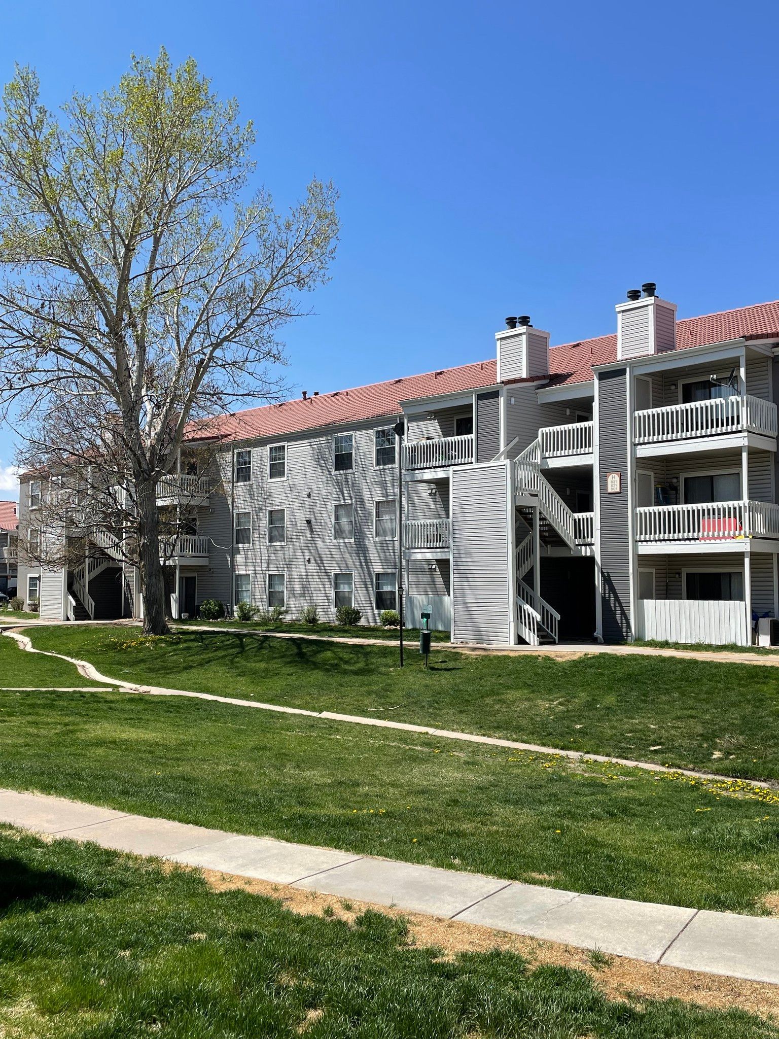 A large apartment building with a lush green lawn in front of it.
