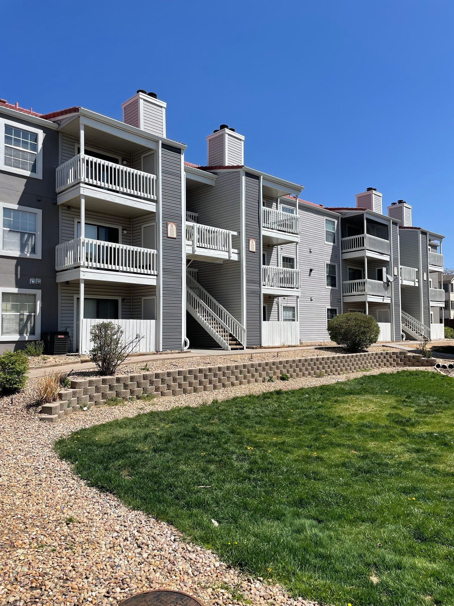 A large apartment building with a lush green lawn in front of it.