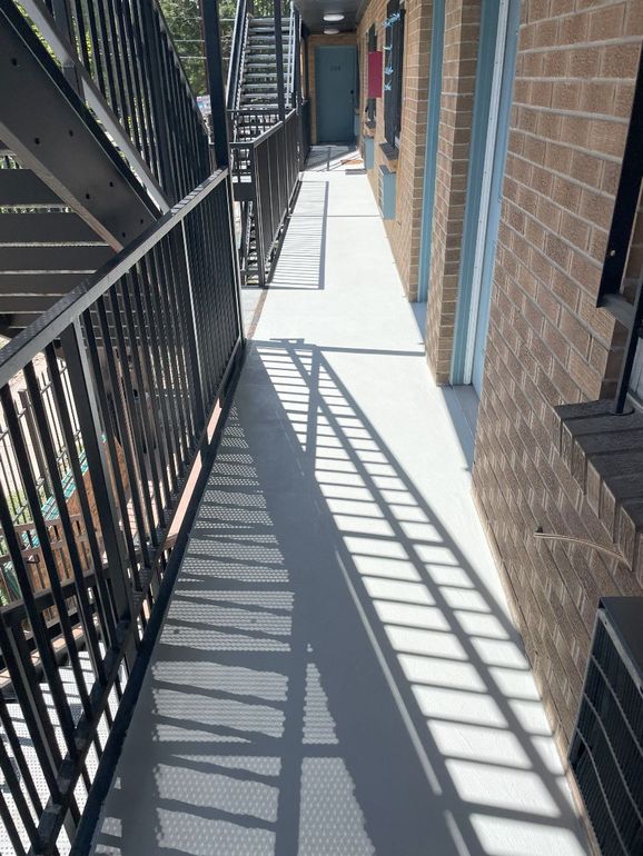 A long hallway between two buildings with stairs and a fire escape.