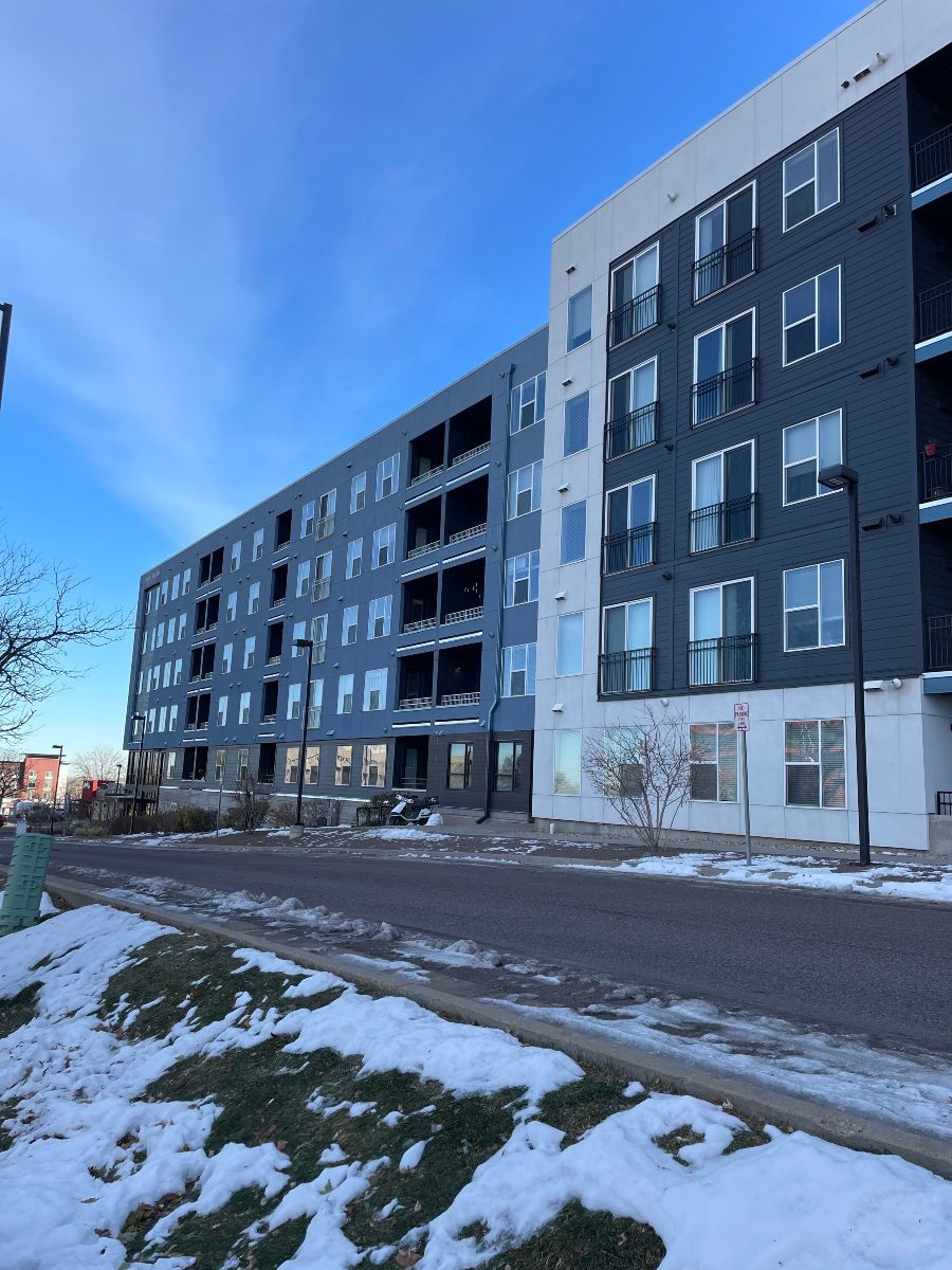 A large apartment building with snow on the ground in front of it