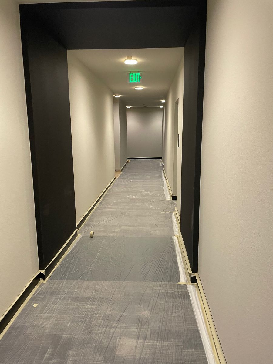 A long hallway with a green exit sign on the ceiling