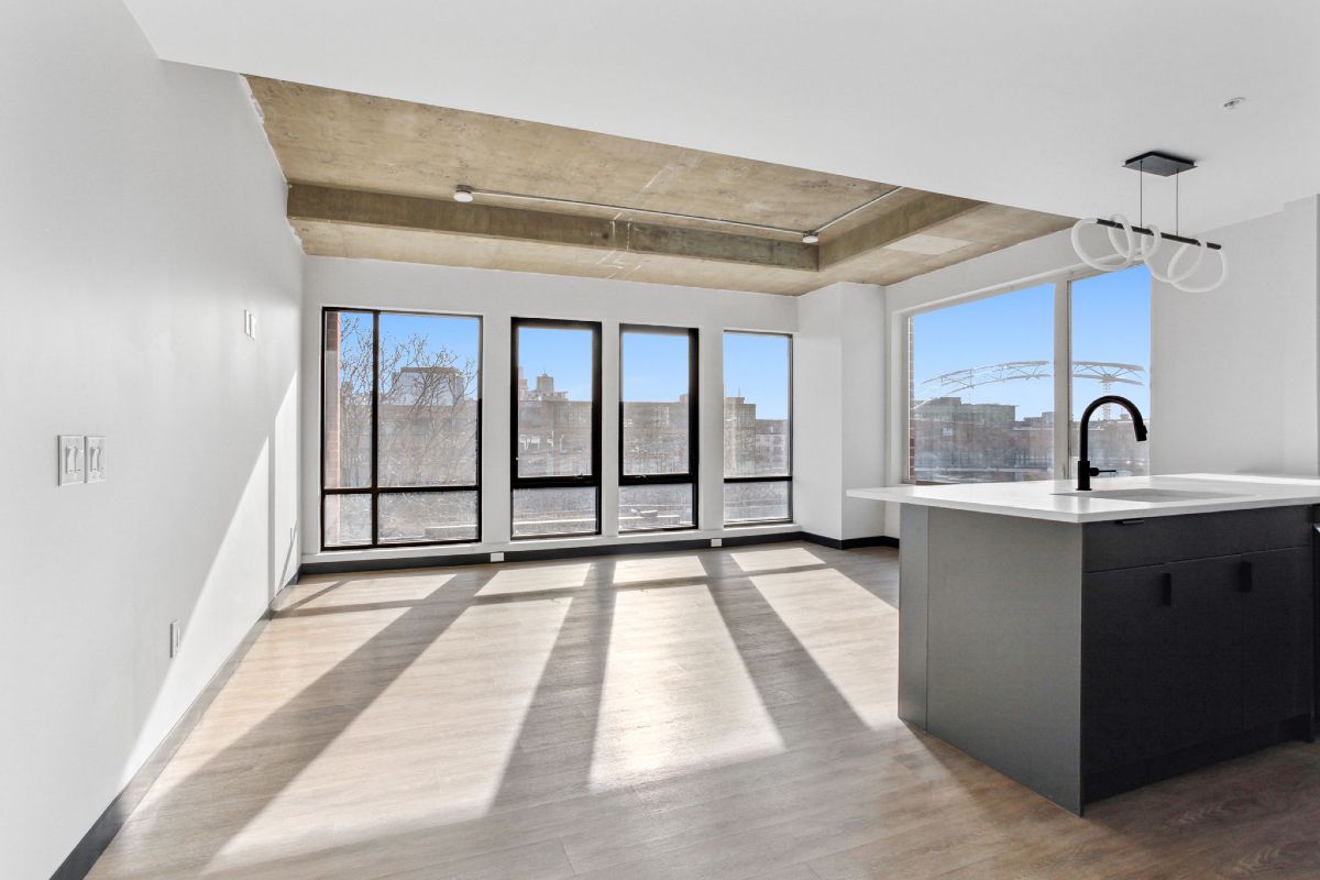 A large empty room with a kitchen and a lot of windows