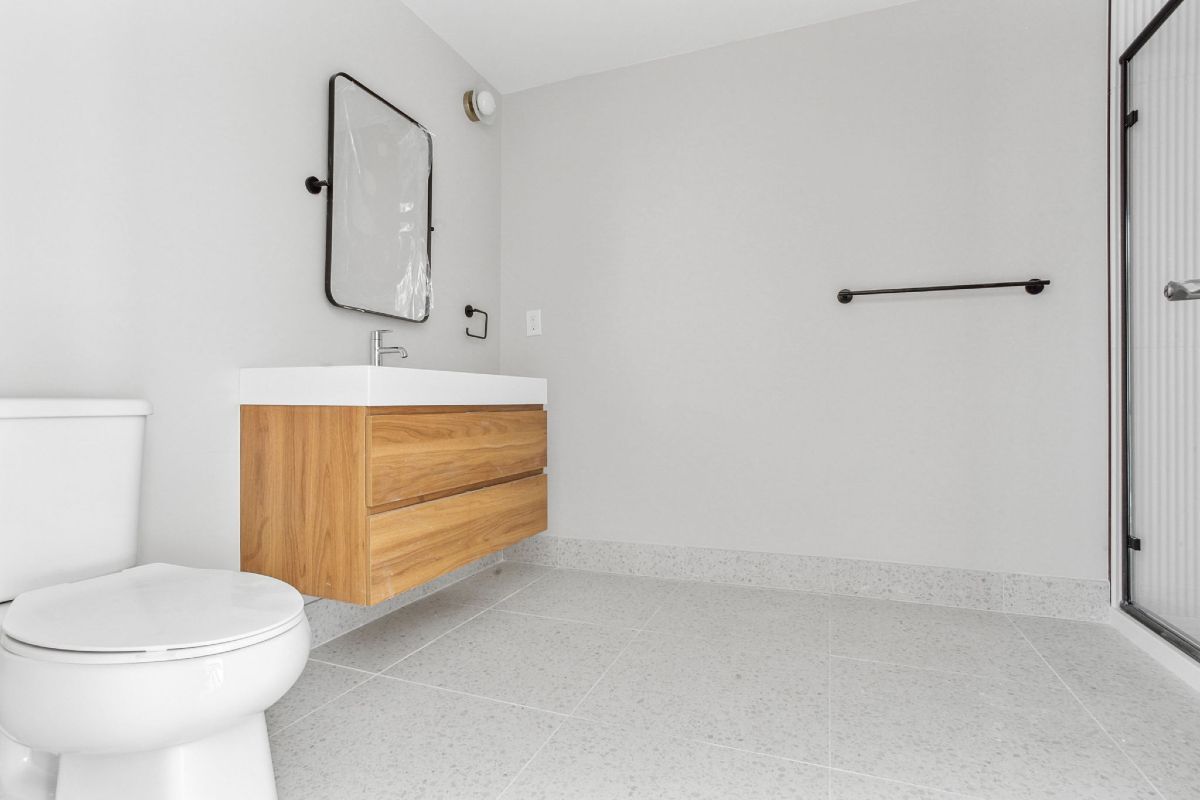 A bathroom with a toilet , sink , mirror and shower.