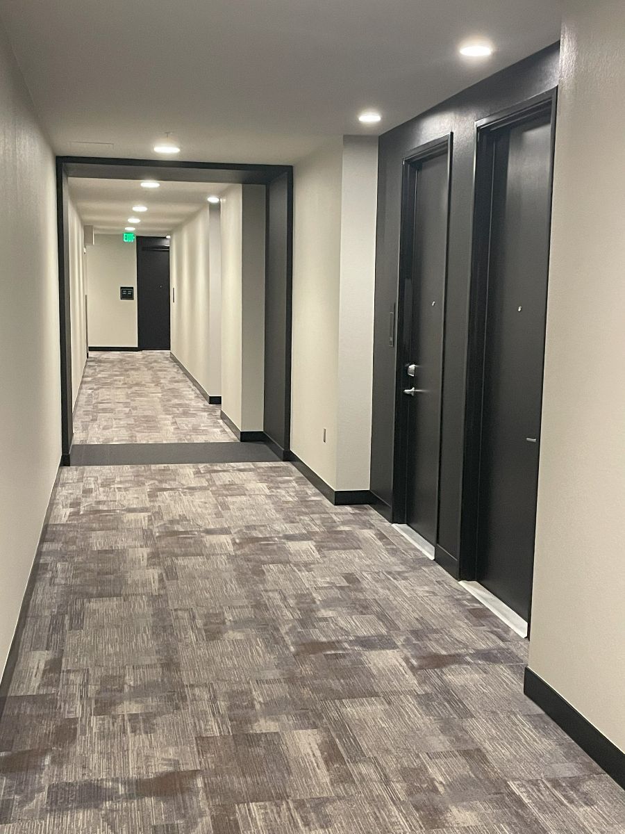 A long hallway with a carpeted floor and black doors.