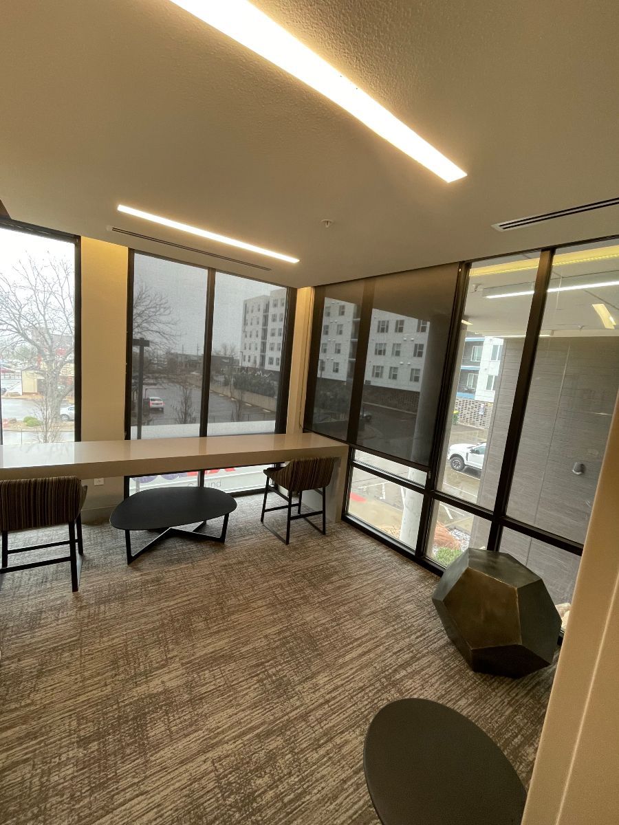 A living room with a table and chairs and a lot of windows.
