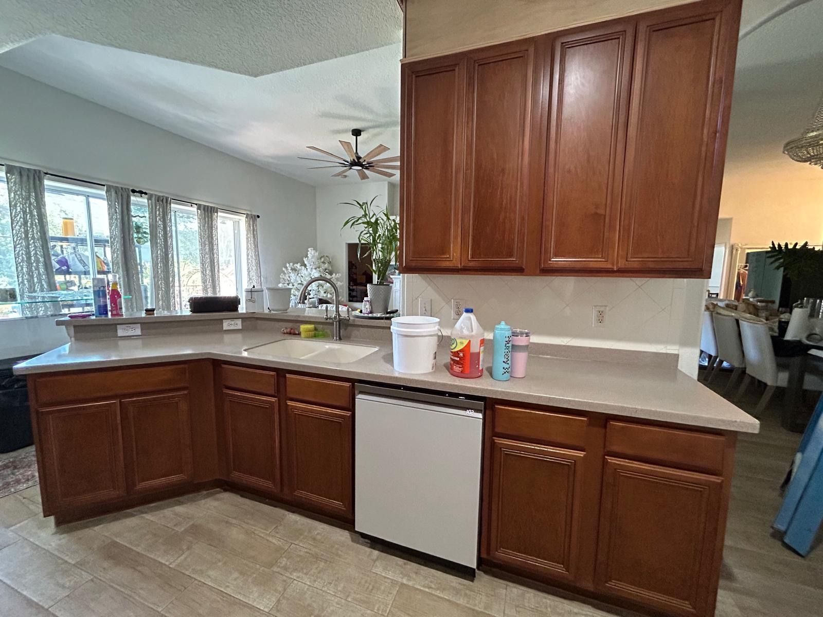 Kitchen with brown cabinets, light countertops, dishwasher, and a window.