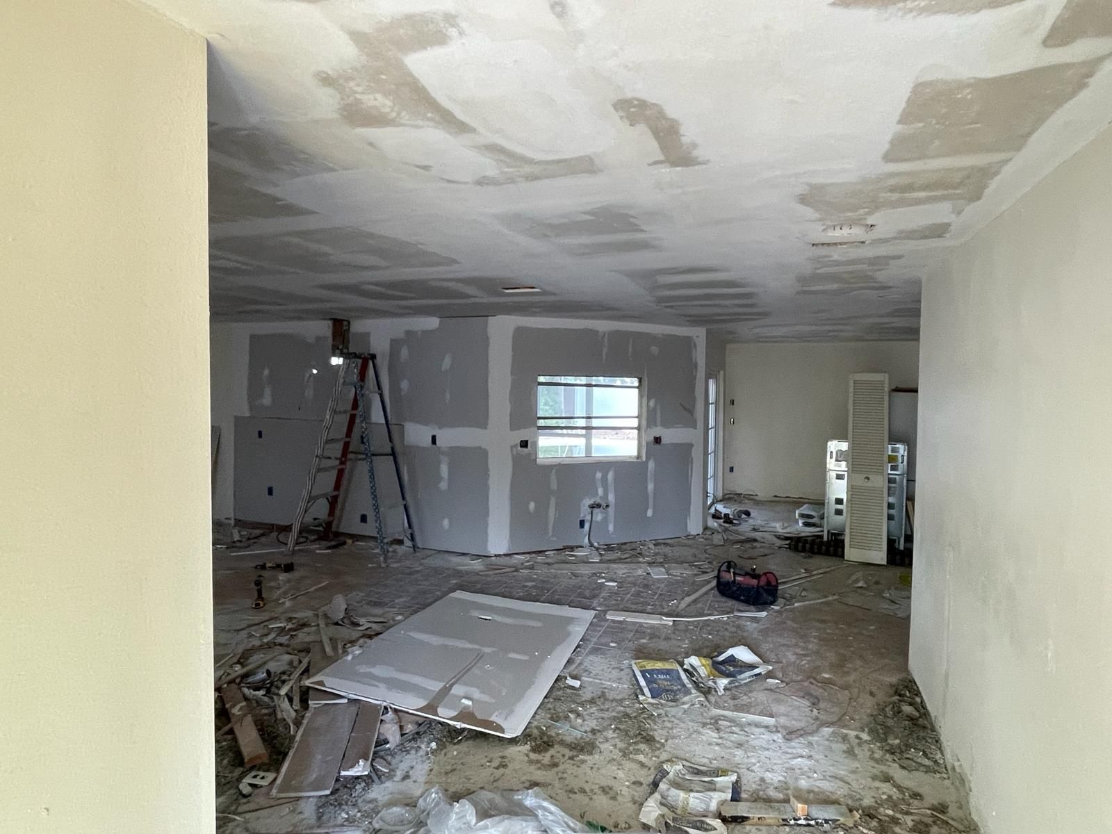 Interior view of a room under construction with exposed drywall and debris on the floor.